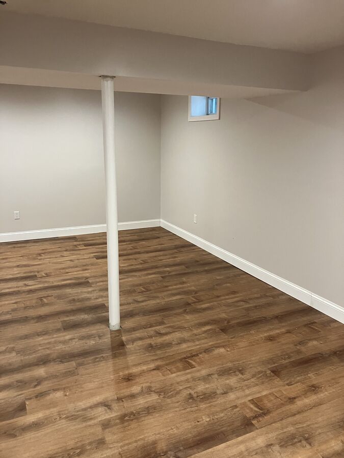 Finished basement — open area with wrapped support column, LVP flooring, baseboard trim