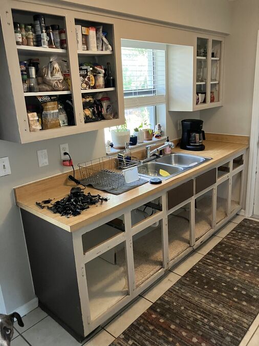 Kitchen before refresh — cabinets stripped, doors removed